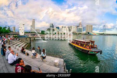 Bum Boat Crusing nel Fiume Singapore con lo skyline di Merlion e Marina Bay sullo sfondo. Foto Stock