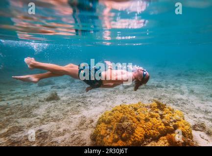 Diving ragazzo adolescente snorkeling in occhiali subacquei facendo bolle sopra le barriere coralline foto subacquea nella laguna turchese pulita su le Morne bea Foto Stock