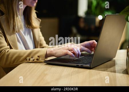 Le mani femminili scrivono sulla tastiera del computer portatile, primo piano. Donna che utilizza un notebook in ufficio. Lavoro online Foto Stock
