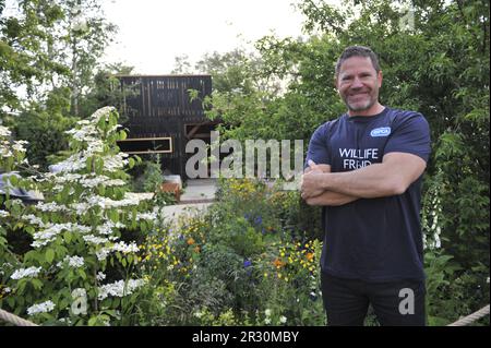 Steve Backhall (presentatore della TV della fauna selvatica) in piedi vicino al giardino RSPCA, uno dei giardini del santuario in esposizione al giorno di apertura 2023 di Chelsea Flower Show di RHS. Chelsea è l'evento di fiori e giardini più prestigioso al mondo. Lo spettacolo di sei giorni attrae circa 168.000 visitatori, inclusi i membri della famiglia reale, ed è il culmine di eventi di fiori e giardini che mostrano giardini all'avanguardia, design all'avanguardia e concetti artigianali, come la settimana della moda di Londra. Il cuore dello spettacolo è il grande padiglione di 12.000 m2, che ospita splendide mostre floreali e un piano espositivo globale di vivai Foto Stock