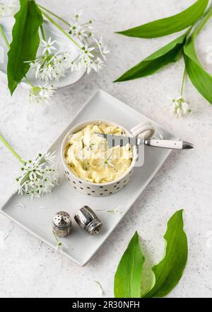 Vista dall'alto del burro alle erbe fatto in casa con fiori di aglio selvatico fresco. Spuntini semplici e salutari e aperitivo. (Allium ursinum) Copia spazio. Foto Stock