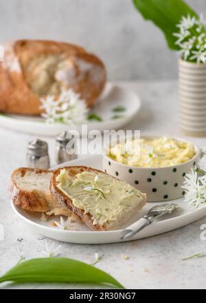 Fetta di pane a pasta madre con burro fatto in casa di aglio selvatico, fiori di ramsons. Concetto di alimento sano dell'erba. Messa a fuoco selettiva. Foto Stock