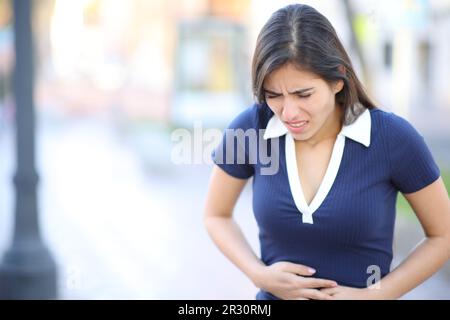 Donna che soffre mal di pancia camminare per strada Foto Stock