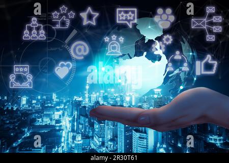 Le mani della donna con l'immagine della terra e le icone dei social network sullo sfondo della città notturna. Concetto di comunicazione mobile globale e di social network Foto Stock