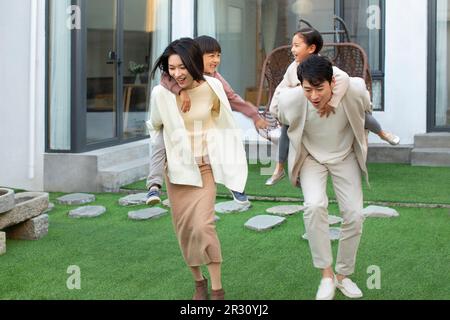 Felice giovane famiglia cinese che gioca nel cortile Foto Stock