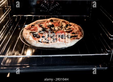 pizza fatta in casa con peperoni, funghi, olive e mozzarella, preparata per la cottura in forno Foto Stock