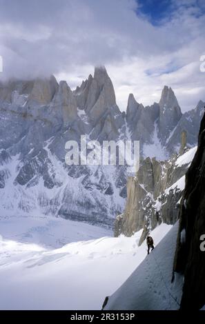 Arrampicatore sul fronte est di Cerro Torre con le cime di Aguja Poincenot, Aguja Rafael e Aguja Saint Exupery sullo sfondo. Foto Stock