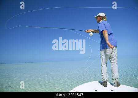 Un pescatore di mosca getta la sua linea nelle Bahamas. Foto Stock