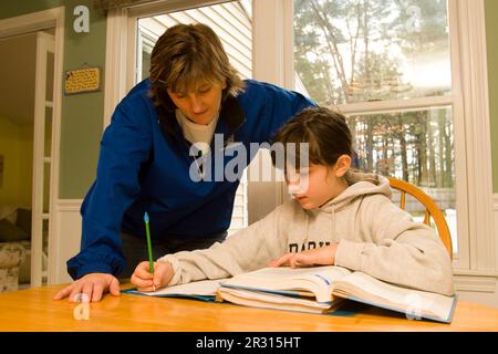 Una madre aiuta la figlia di dieci anni con i compiti a casa. Foto Stock