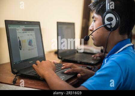 Ragazzo peruviano che impara l'inglese usando i computer in una classe Foto Stock