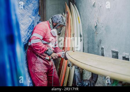 Un surf shaper locale di Tenerife che lavora su una nuova tavola da surf Foto Stock