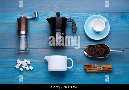 Composizione piatta con macinacaffè manuale e macchina per caffè geyser su sfondo di legno azzurro Foto Stock