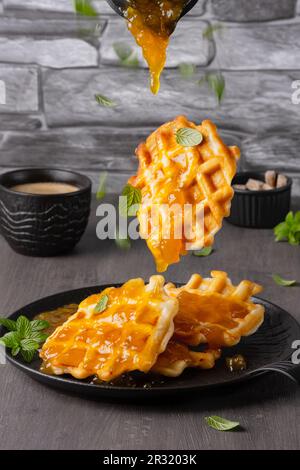 Cialde volanti e menta caduti con marmellata di mango uno sfondo grigio Foto Stock