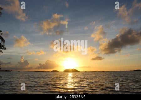 alba sul mare dei Caraibi e un'isola con acqua blu scuro e forme nuvolose sullo sfondo Foto Stock