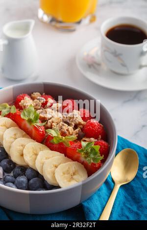 Ciotola di granola d'avena con yogurt, lamponi freschi, mirtilli, fragole, banana e noci su tovagliolo d'acqua per una sana colazione. Sfondo bianco. Foto Stock