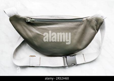 lato posteriore della borsa da cintura verde in pelle chiusa sul bordo grigio primo piano Foto Stock