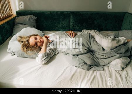 Bella donna in pigiama giace sul letto al mattino. Foto Stock