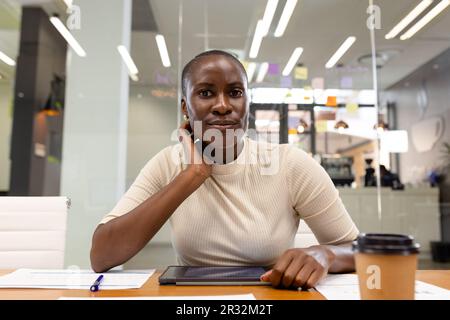 Ritratto di donna d'affari afroamericana con tablet digitale e caffè sulla scrivania seduto in ufficio Foto Stock