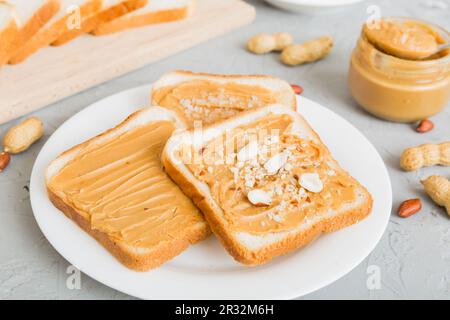 Panini al burro di arachidi o toast su un tavolo chiaro sfondo.Breakfast. Cibo vegetariano. Cucina americana vista dall'alto con spazio copia. Foto Stock