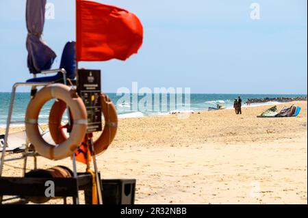 Sedia bagnino con bandiera rossa su una spiaggia di sabbia quasi vuota con aquiloni sdraiati nella sabbia a Mui NE, Vietnam. Foto Stock