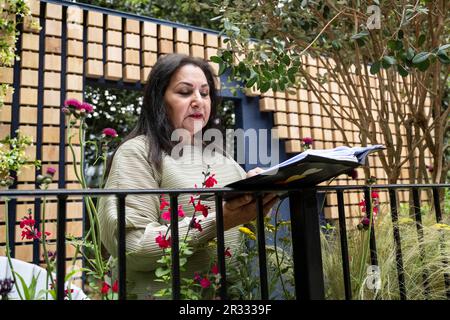 Londra, Regno Unito. 22 maggio 2023. Il pluripremiato poeta Imtiaz Dharker legge una poesia da una delle edizioni della Folio Society al Reading Room Garden della Folio Society durante il giorno della stampa della RHS Chelsea Flower Show nei terreni del Royal Hospital Chelsea. Lo spettacolo si svolge fino al 27 maggio 2023. Credit: Stephen Chung / Alamy Live News Foto Stock