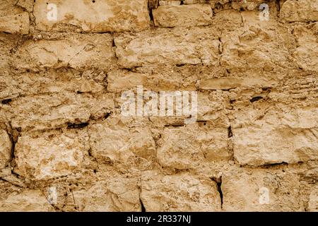 struttura orizzontale di vecchio muro in arenaria bruna grossa, con vecchio intonaco fessurato in argilla Foto Stock