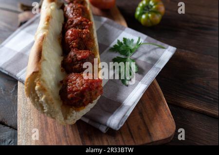 Sandwich con polpette con salsa di pomodoro e mozzarella fusa su tavolo di legno. Foto Stock