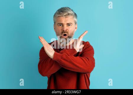 Immagine di un uomo arrabbiato di mezza età che fa un gesto a mani incrociate Foto Stock