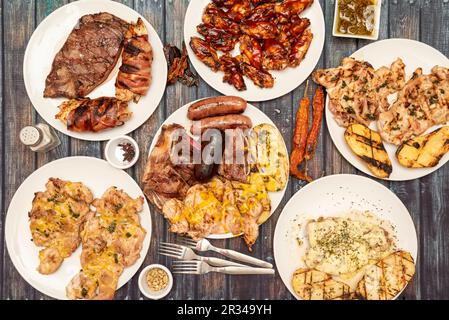 Ancora vita con piatti di cibo cucinati alla griglia, con filetti di pollo, chorizos e budino nero, ali di barbecue, purè di patate e peperoncino secco Foto Stock