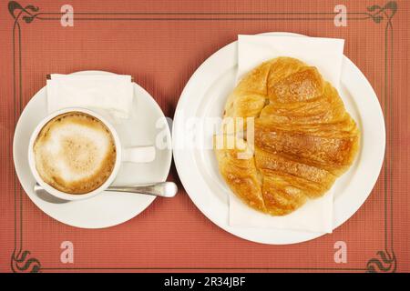 Una colazione semplice e tipica a base di caffè con latte e croissant appena sfornati Foto Stock