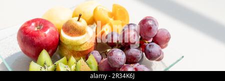 Materie frutti bacche platter, mango, arance e kiwi fragole, mirtilli pompelmo uva, banane mele sulla piastra bianca, sul bianco tabl Foto Stock