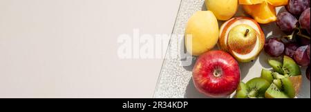 Materie frutti bacche platter, mango, arance e kiwi fragole, mirtilli pompelmo uva, banane mele sulla piastra bianca, sul bianco tabl Foto Stock