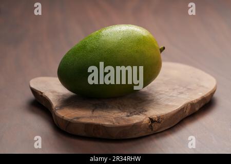 Mango verde maturo lavato e pronto da mangiare su tavola di legno, messa a fuoco superficiale Foto Stock