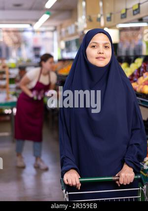 Ritratto di giovane donna acquirente in hijab in supermercato Foto Stock