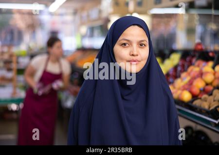 Ritratto di giovane donna acquirente in hijab in supermercato Foto Stock