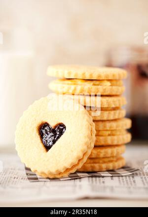 Una pila di biscotti sandwich con marmellata e crema con finestre a forma di cuore Foto Stock