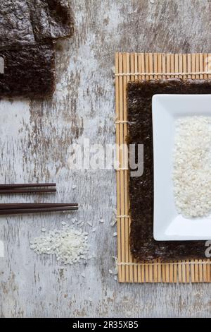 Ingredienti per il sushi su un tappetino di bambù Foto Stock