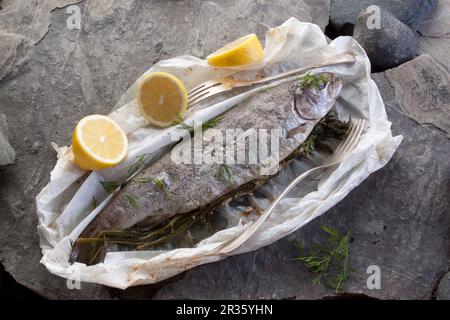 Trota intera arrosto con aneto e limone in carta pergamena Foto Stock