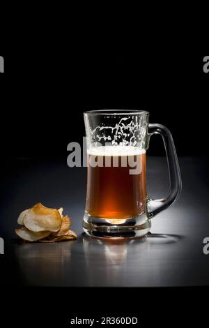 Un bicchiere di birra scura e patatine Foto Stock