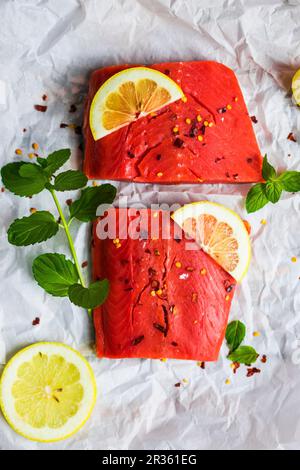 Materie di salmone selvatico con la menta, limone e spezie su un pezzo di carta bianca Foto Stock