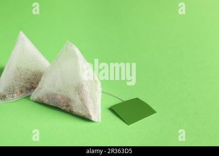 Nuove bustine di tè con linguette su sfondo verde, primo piano. Spazio per il testo Foto Stock