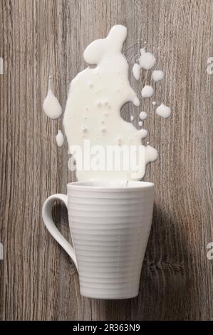Una tazza di latte versato (vista dall'alto) Foto Stock