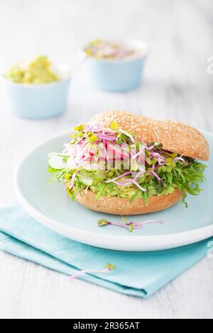 Un bagel con il cetriolo e avocado, germogli di rafano e ravanelli Foto Stock