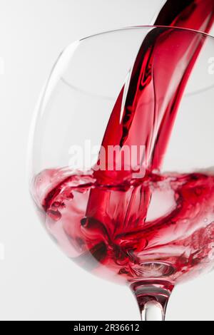 Il vino rosso è versata in un bicchiere da vino Foto Stock