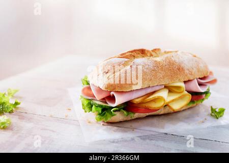Baguette con prosciutto, formaggio, verdure e lattuga Foto Stock