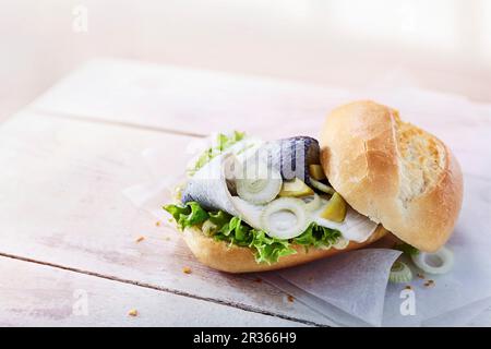 Baguette con Bismarck aringhe, cetriolini, lattuga e cipolle Foto Stock