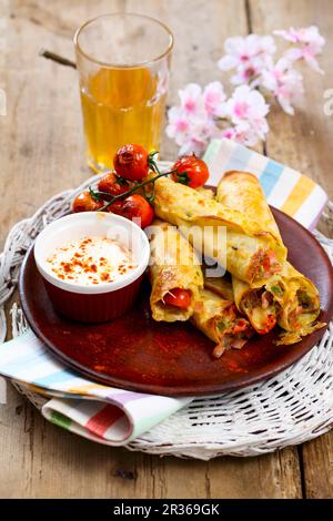 Pancake ripieni di formaggio, prosciutto, funghi e erba cipollina serviti con pomodori arrostiti al forno e panna acida Foto Stock