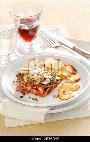 Foglio Illustrativo con prosciutto e formaggio Grayerzer servito con patate croccanti patatine Foto Stock