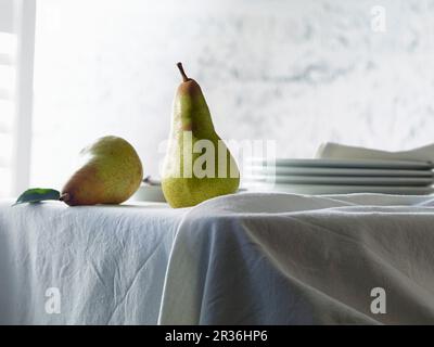Due pere Abate Fetel su un tavolo con una tovaglia bianca Foto Stock