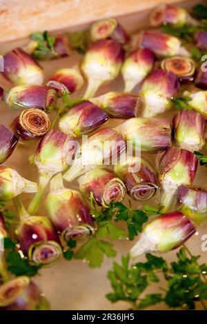 Carciofi e prezzemolo in una ciotola d'acqua Foto Stock